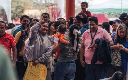 Familias y asistentes se reúnen en el Concurso de Gateo de la Feria de Tlaxcala; una mujer sonríe y otra carga a un bebé