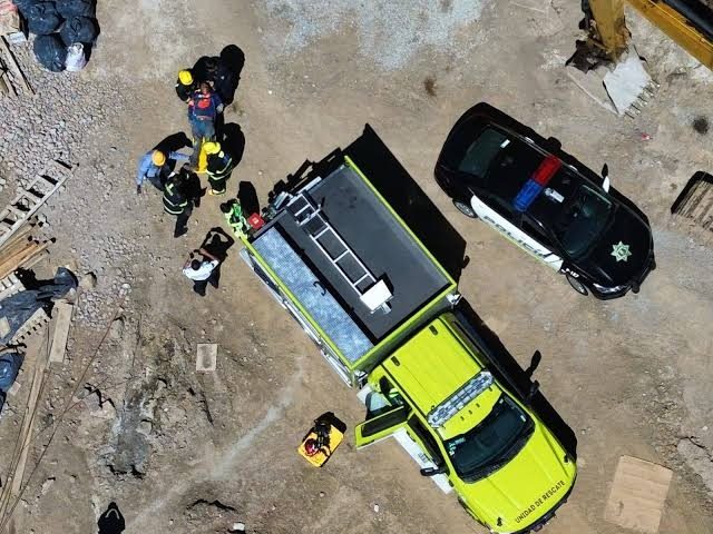 Vista aérea de rescatistas con casco junto a un camión de rescate y una patrulla en la obra de Ciudad de la Inclusión,...
