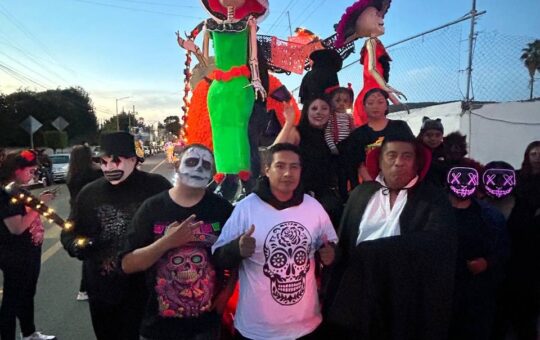 Participantes disfrazados y con maquillaje de calavera posan junto a catrinas monumentales en el desfile de Panotla