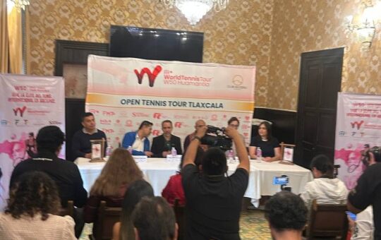 Rueda de prensa del torneo W50 de tenis: cinco personas en una mesa ante una lona, con periodistas y un camarógrafo