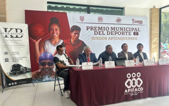 Cinco hombres sentados a una mesa, en Apizaco, ante una lona del Premio Municipal del Deporte y Juegos Apizaquenses